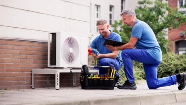 Two men fixing a heat pump