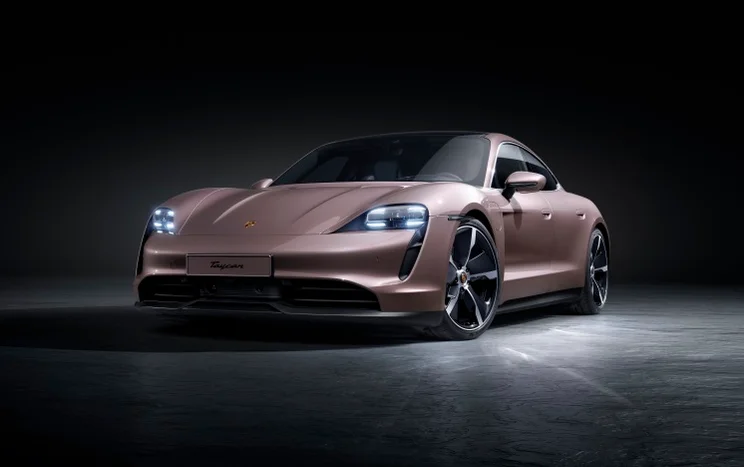The Porsche Taycan Plus on a grey floor, against a black background