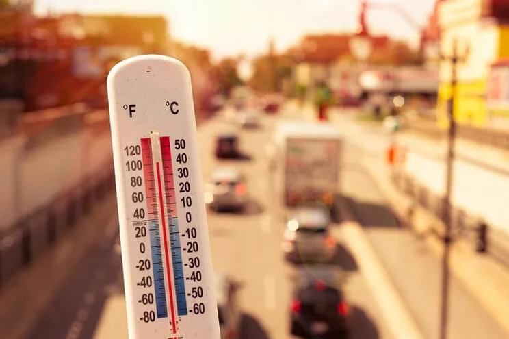 Thermometre showing 38 degrees Celsius in front of cars and traffic during a heatwave