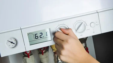woman adjusting temperature on boiler