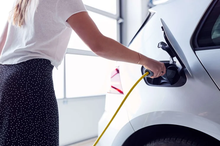 woman plugging charger into electric vehicle