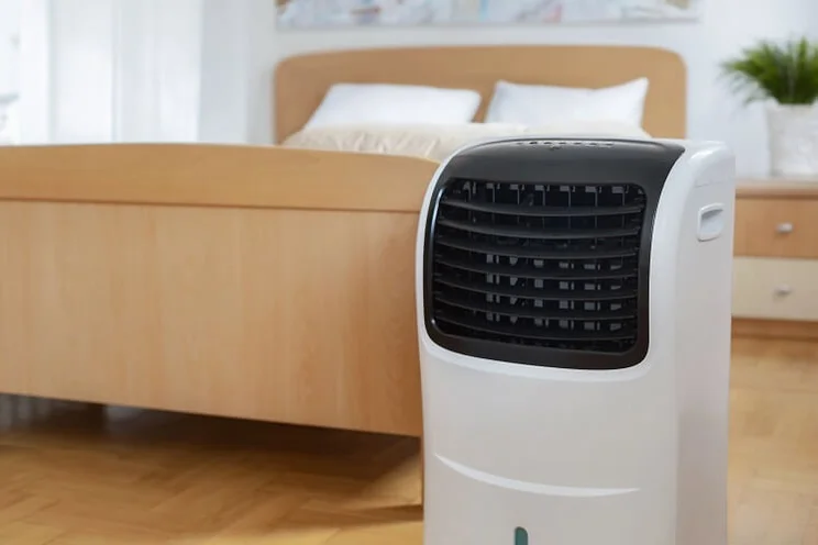 portable heat pump in bedroom near bed