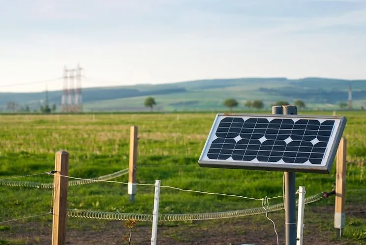 solar panel on fence with grass fields and hills on background